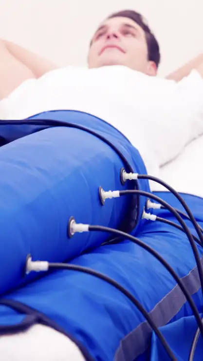 Hombre tumbado recibiendo un tratamiento corporal de presoterapia con las piernas tapadas por el instrumental del tratamiento